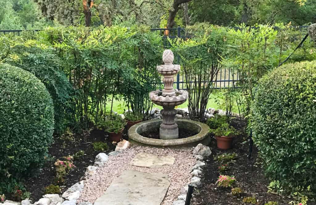 Nandina growing in landscaping around a water fountain and bird bath.